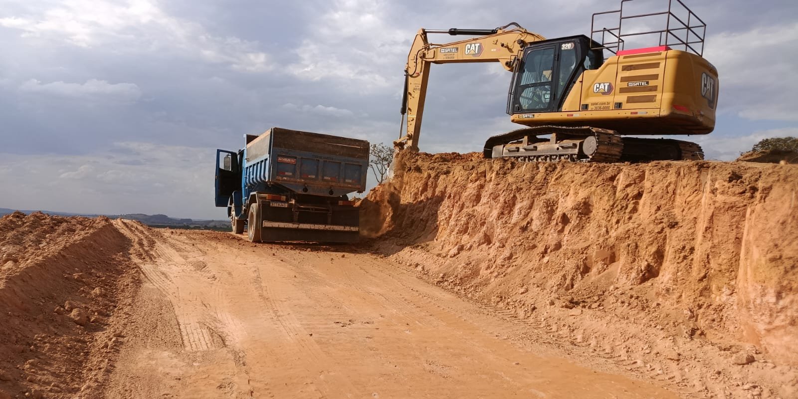 Escavadeira carregando caminhão em corte de terraplenagem da Gidê
