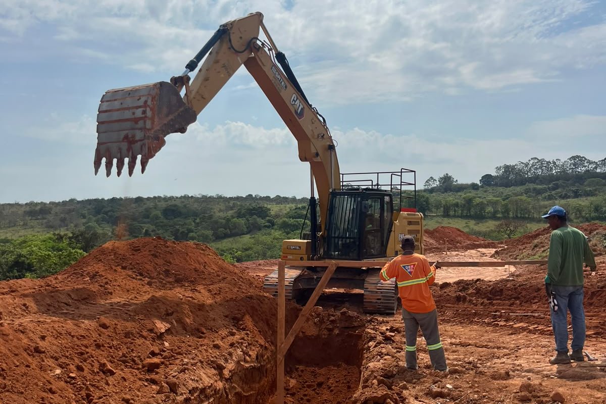 Escavadeira e equipe em obra de drenagem pluvial