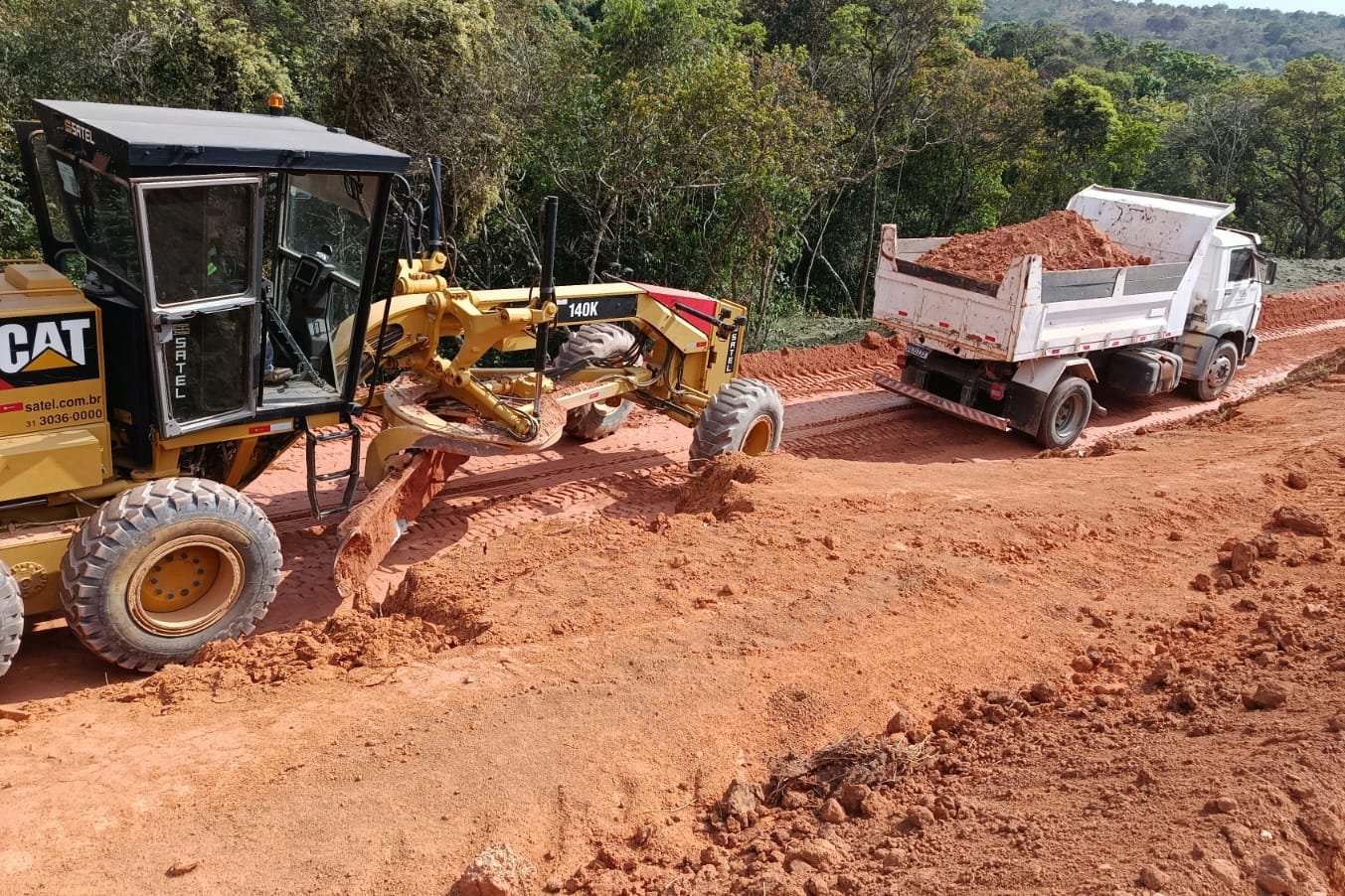 Motoniveladora e caminhão em obra de terraplenagem